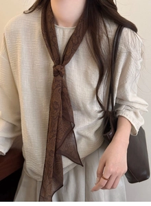 Close-up of a dark brown paisley pattern fabric scarf necklace with retro aesthetic