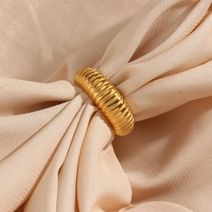 Detail of 18K gold plated stainless steel ribbed ring on soft beige silk fabric