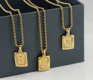 Detailed shot of 18K gold plated square letter pendants A, L, and G on twist chains