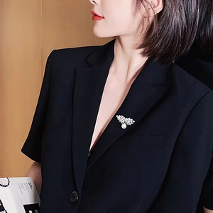 Elegante Silberflügel-Brosche mit weißer Perle auf schwarzem Blazer für stilvolle Frauen