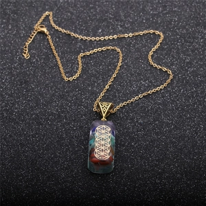 Detail of colorful resin pendant with layered stones and flower of life on gold chain