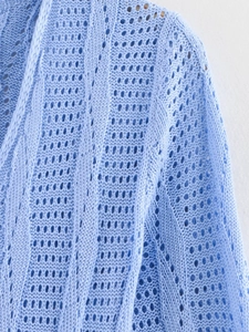 Detaillierte Nahaufnahme des hellblauen Strickoberteils mit Ajour- und Zopfmustern