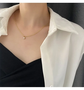 Detail shot of a minimalist gold titanium necklace with a purple pearl pendant on a model