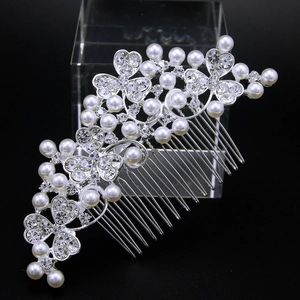 Close-up of silver hair comb with faux pearls and rhinestones on acrylic stand