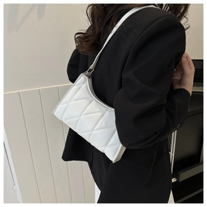 White quilted underarm bag with gold hardware worn on a model's shoulder for a minimalist look