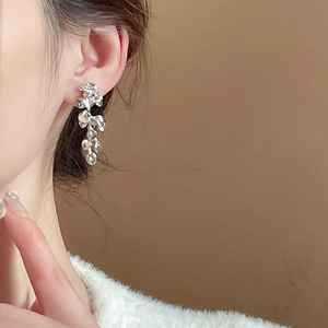 Detailed close-up of textured silver flower tassel earrings with irregular lava pattern style