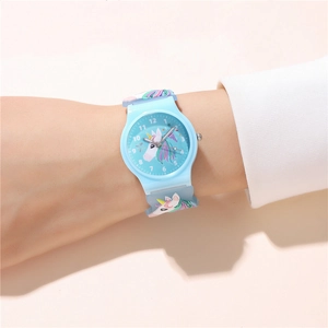 Close-up of light blue kids watch featuring 3D unicorn strap and rainbow dial details
