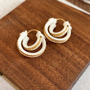 Detailed macro view of 18k gold plated double hoop earrings on a dark wood display stand