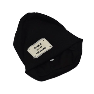 Dettaglio di un berretto nero in maglia con etichetta in cotone vintage e testo