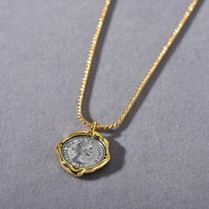 Macro shot of gold and silver tone coin pendant featuring an embossed royal portrait detail