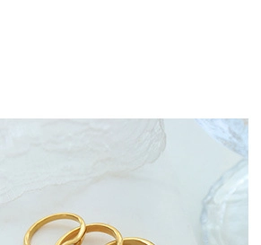 Macro view of gold-plated minimalist stacking rings on textured white fabric