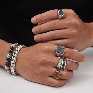 Close-up of men's stainless steel rings and bracelets styled with turquoise and tiger eye stone
