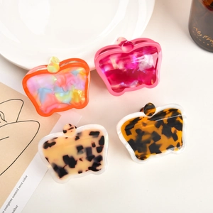 Flat lay of four acetate hair claws in marble and tortoiseshell patterns on a tray