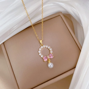 Detail of gold necklace featuring pink heart stones, zircons and a pearl drop charm