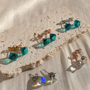 Sparkling square crystal earrings in assorted colors on natural stone background