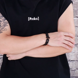 Detail of black woven leather bracelet with metal cross clasp worn on man's wrist