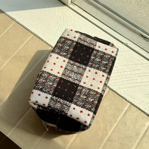 Detailed view of black and white checkered wool cosmetic bag with red dots and metal zipper