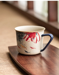 Detail of ceramic coffee cup featuring gold-painted koi fish and blue lotus patterns