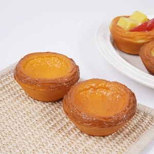 Realistic 7.5cm PU egg tart model with flaky crust and fruit toppings on a woven mat