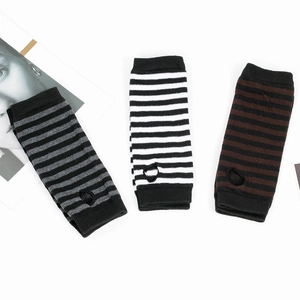 Detailed view of striped knitted arm warmers in gray, black, and white with thumb holes