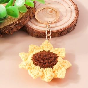 Handmade crochet sunflower keychain with golden metal ring on a rustic wooden slice