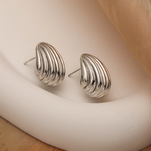 Orecchini a spirale in argento con texture a conchiglia su supporto scultoreo elegante