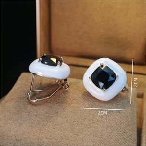 Detail view of square candy stud earrings featuring black zircon and white resin