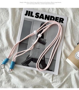 Detail of pink woven bag strap with blue cord accents and silver metal spring rings