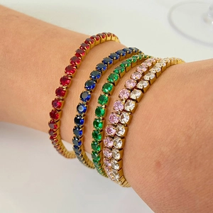 Gros plan de cinq bracelets tennis plaqués or 18 carats avec zircons colorés sur un poignet