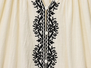 Détail de broderie ethnique et boutons blancs sur une chemise rétro en coton et lin