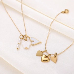 Detailed view of gold stainless steel necklace and bracelet with shell hearts on silk