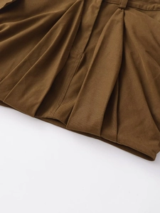 Close-up of deep brown cargo skirt detailing pleated fabric and precision stitching
