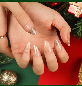 Macro shot of almond press-on nails with golden snowflakes and glitter gradient design