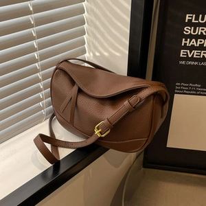 Detailed view of brown litchi grain leather bag with golden buckle and adjustable strap