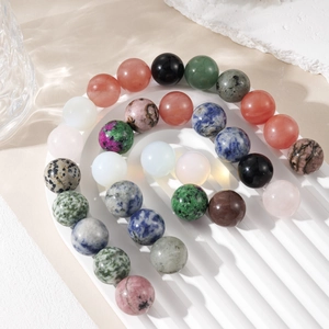 Close-up of polished 16mm natural crystal spheres in various colors on a wavy white tray