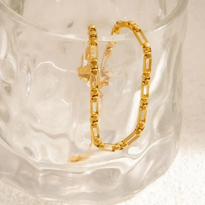 Detail of 18K gold plated rectangular link chain bracelet on textured glass rim
