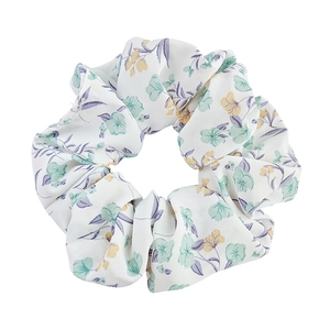 Floral organza scrunchie with green flowers and yellow centers on white fabric