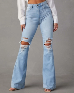 Gros plan sur les genoux déchirés et le denim délavé bleu clair du jean évasé à taille haute