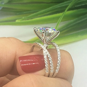 Macro shot of a silver four-prong round zircon ring with crisscross pave diamond bands