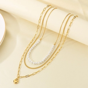 Detailed view of triple-layered gold necklace with heart pendant and pearls on display