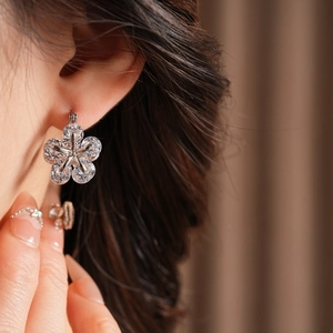 Détail d'une boucle d'oreille fleur argentée avec zircons portés par un mannequin