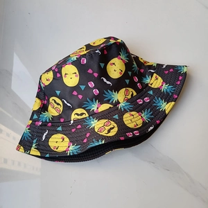 Vue détaillée à plat d'un bob noir élégant orné d'un motif amusant d'ananas en dessin animé