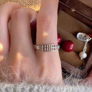Detailed view of an abacus-shaped silver ring on finger with traditional Chinese patterns