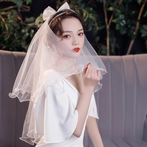 Close-up of elegant double-layered white bridal veil with bow headband and star earrings