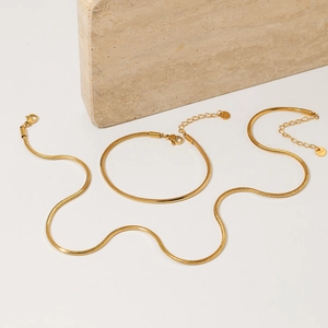 Elegant gold stainless steel snake chain necklace and bracelet set on stone background