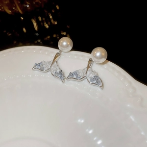 Detailed macro view of silver fishtail stud earrings with pearls and blue crystal stones