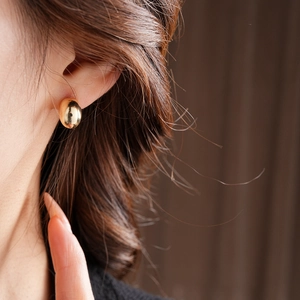 Macro shot of minimalist gold plated bean stud earrings worn for a sleek modern look