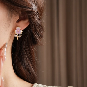 Close-up of elegant flower stud earrings with purple translucent petals and gold frame