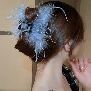 Detail of elegant large hair claw with soft light blue feathers on a bun hairstyle