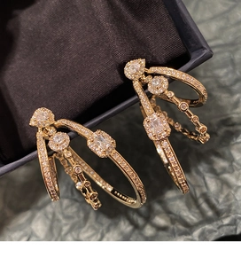 Macro detail of gold-plated geometric hoop earrings with cubic zirconia in a velvet box